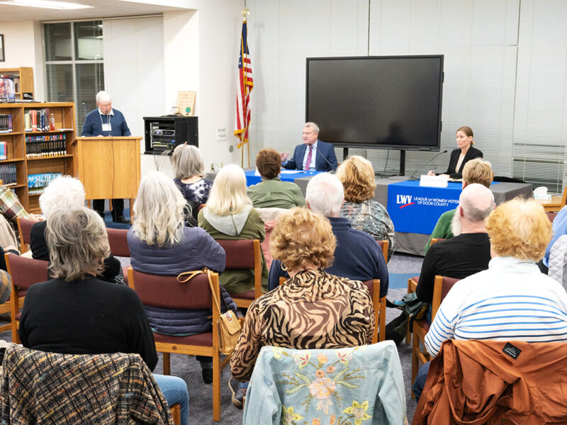 Image of Joel Kitchens and Renee Paplham in front of a small, seated crowd at the Door County League of Women Voters forum in the Southern Door High School library.