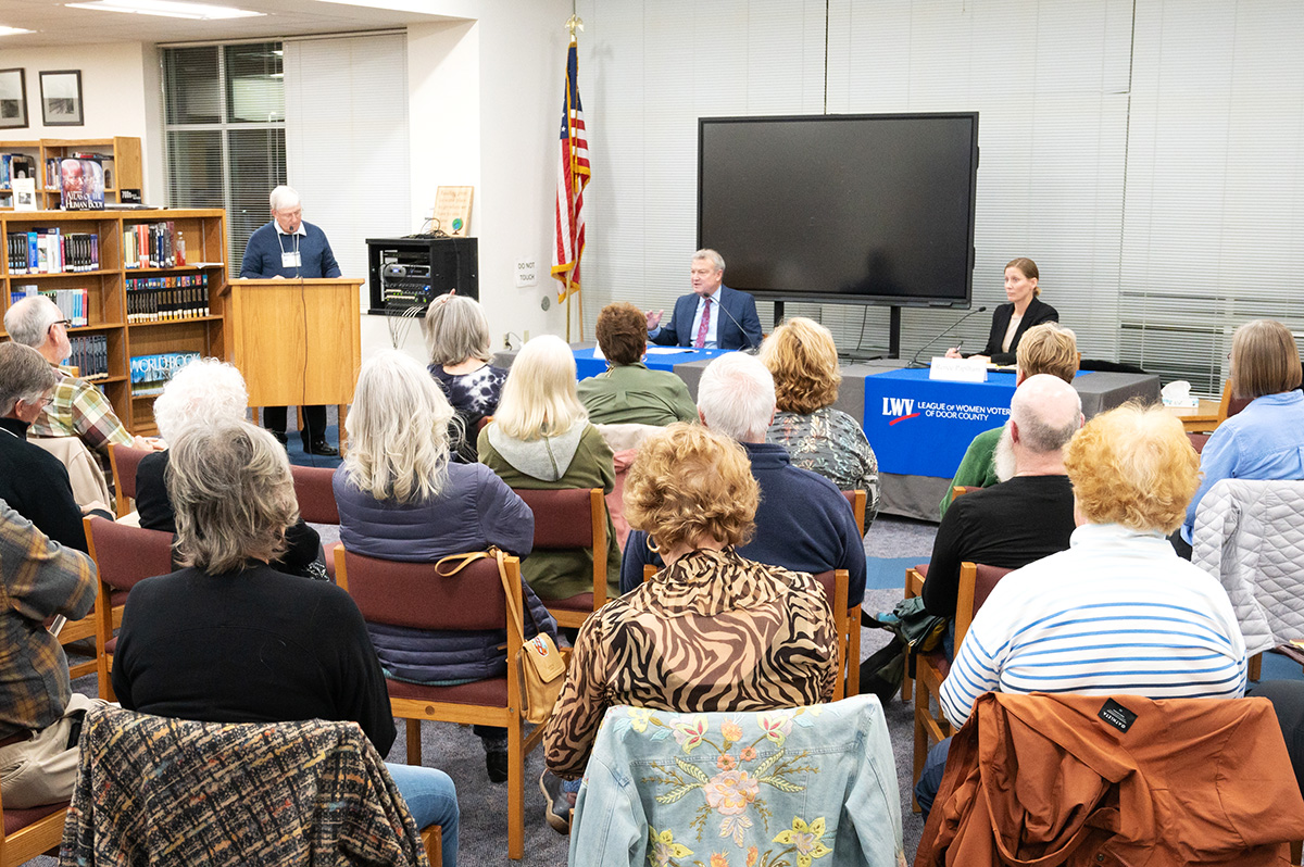 Image of Joel Kitchens and Renee Paplham in front of a small, seated crowd at the Door County League of Women Voters forum in the Southern Door High School library.